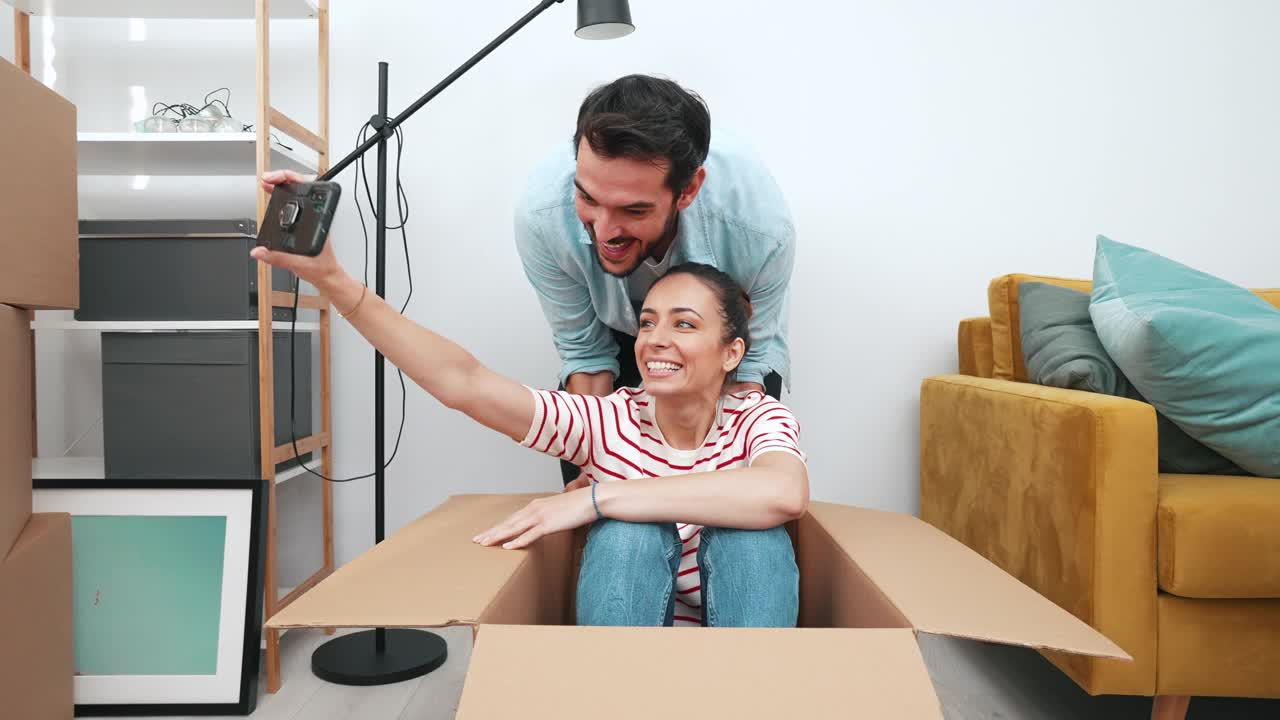 一对快乐的年轻夫妇在他们的新公寓里玩得很开心。视频素材
