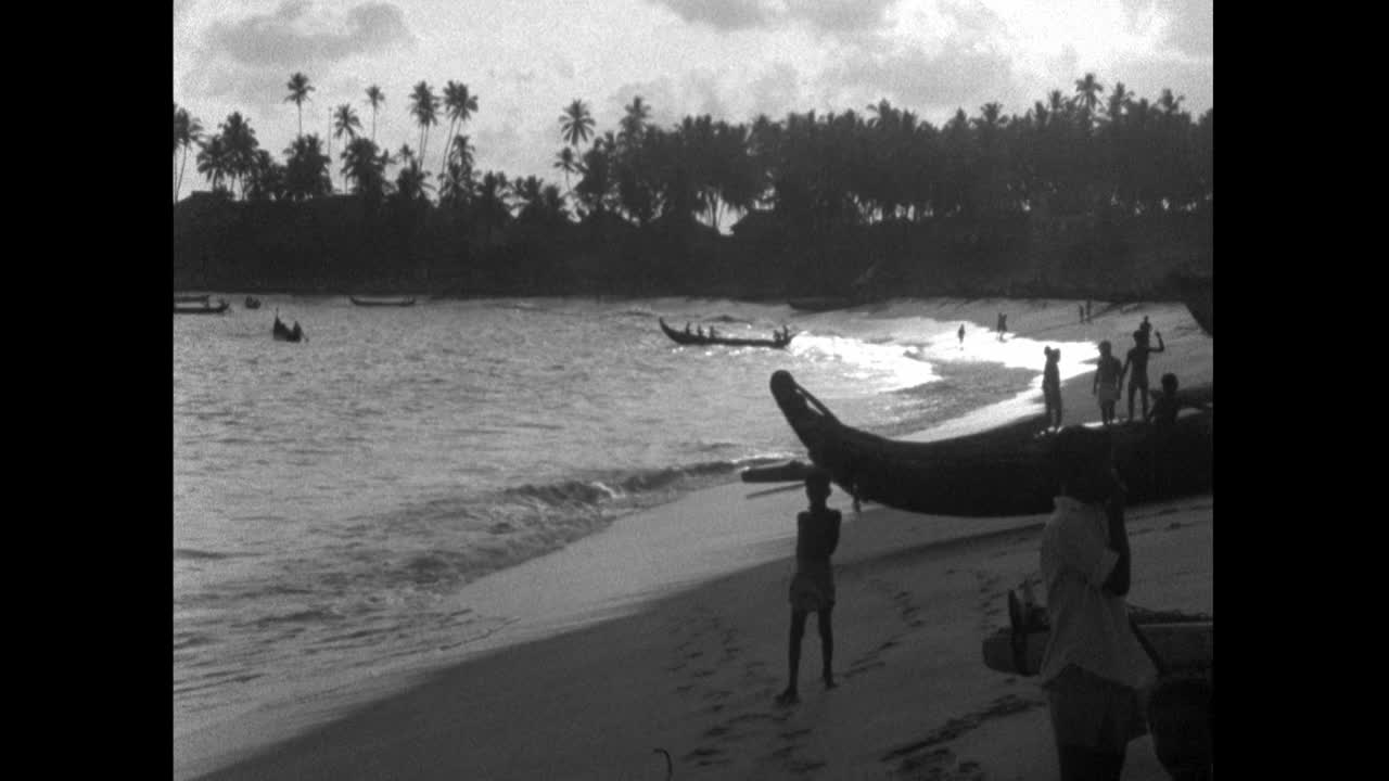 喀拉拉邦日落时海滩上的WS人和船只;1960视频下载