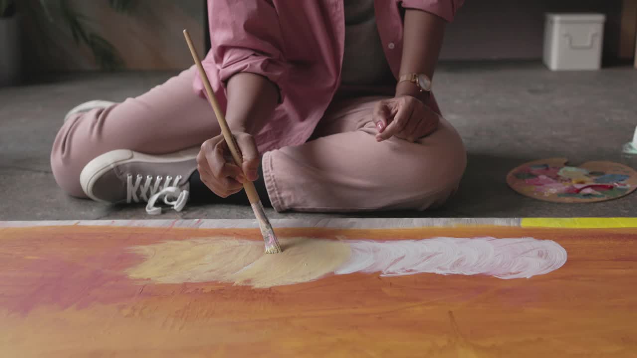 匿名非洲女画家坐在地板上她的家庭工作室和油画在画布上视频下载