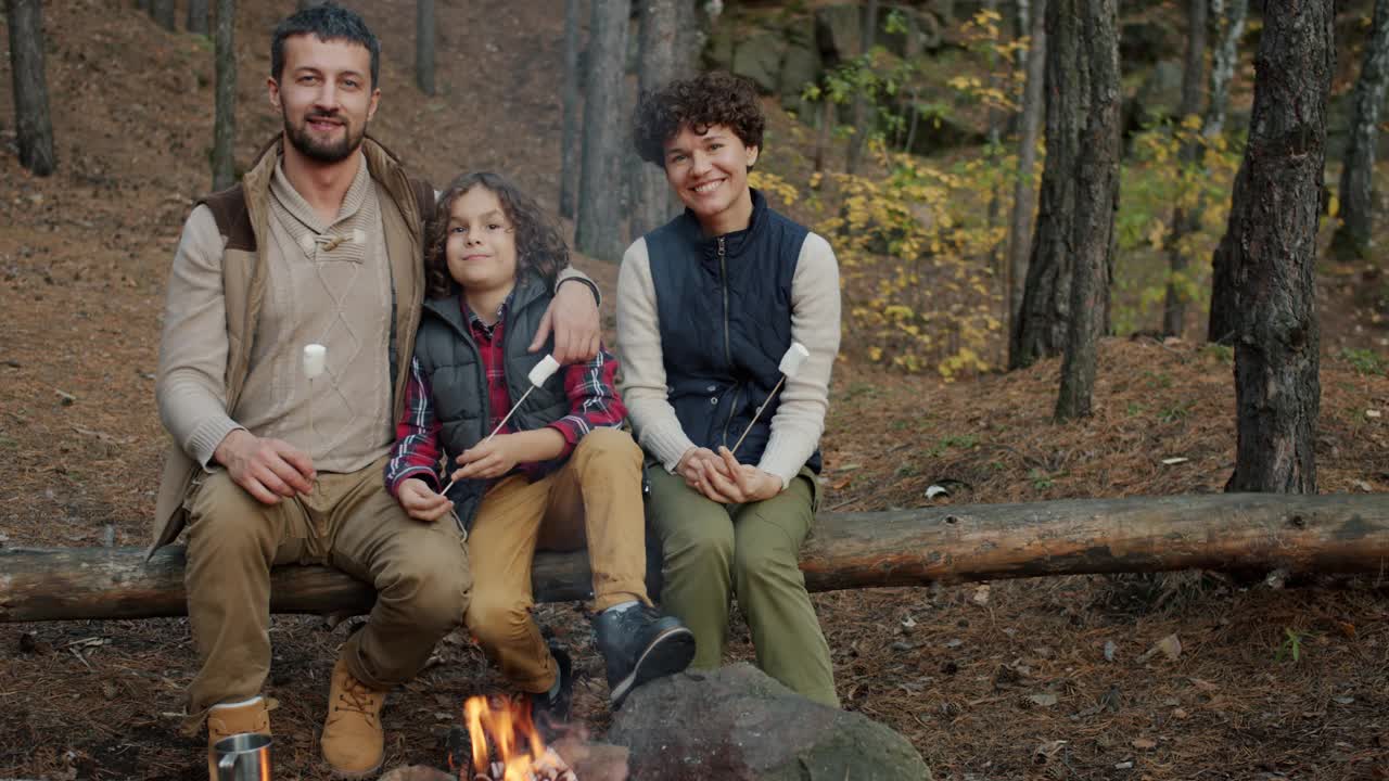 快乐的人们妈妈，爸爸和孩子坐在营火旁的慢动作肖像视频素材