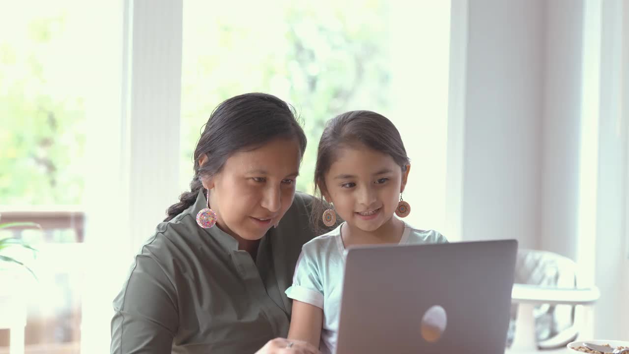 妈妈和女儿在用笔记本电脑视频下载