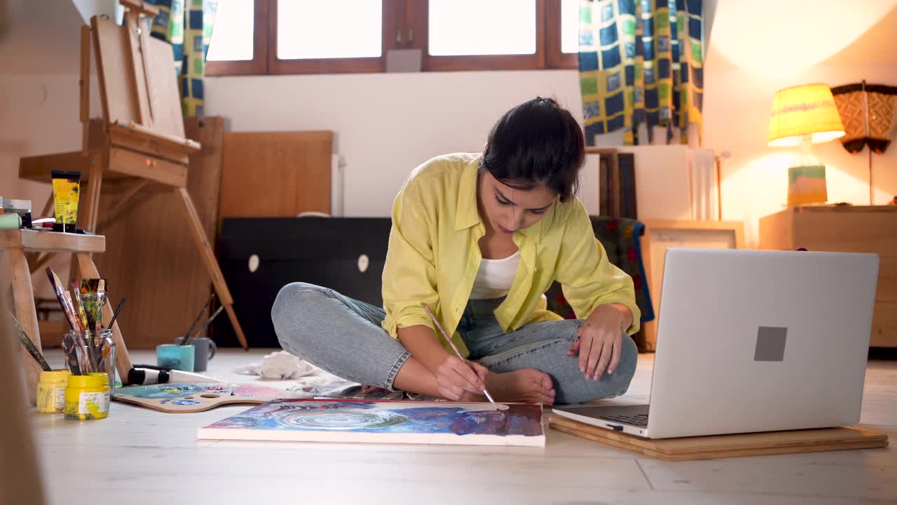创造性的女性艺术家，看在线绘画教程在她的笔记本电脑，以提高她的绘画技能视频下载