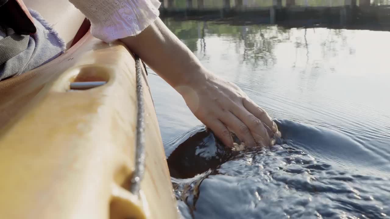 近距离后，年轻的成年妇女手划着皮划艇，划艇在湖上，触摸着清澈透明的水视频下载