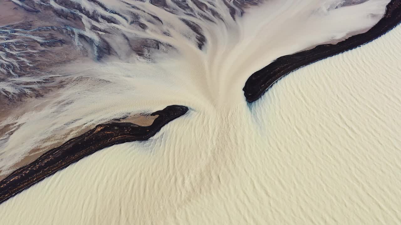 在冰岛，无人机拍摄到黑色沙滩之间的辫状河流入冰川融水视频素材