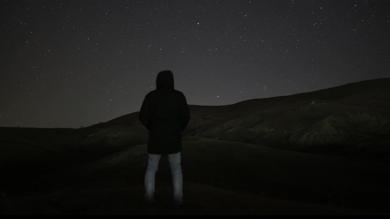 一个人站在繁星满天的夜空的背景下。以琼脂为背景的人观察星系。宇宙是一个奇迹，美丽是时间的运动。视频下载