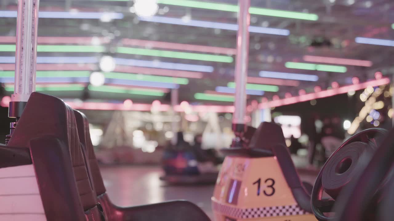 娱乐向后拍摄的翻斗车在闪烁的霓虹灯下的前景和模糊的人驾驶快速闪避车的乐趣视频素材