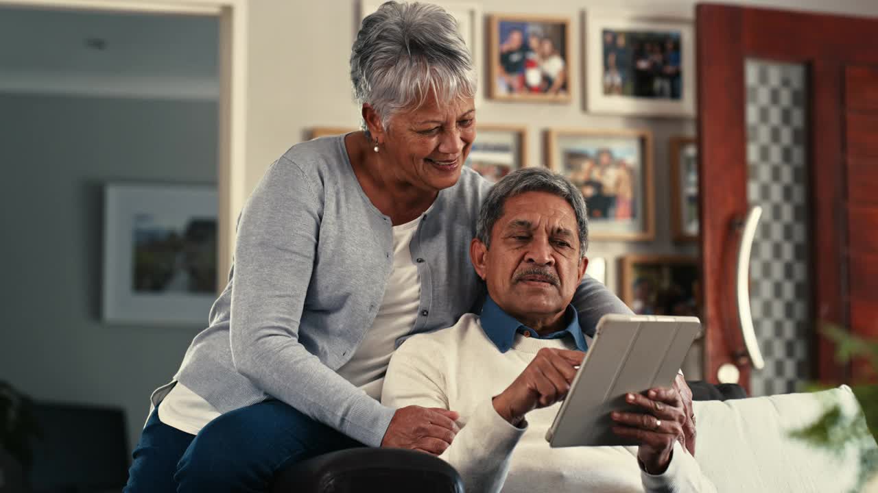 一对老年夫妇在家里的沙发上使用数码平板电脑的4k视频片段视频素材