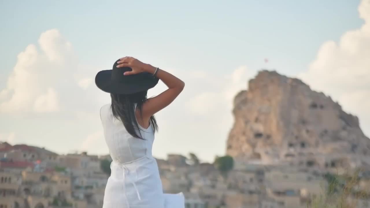 静态视图年轻的女性游客在白色的衣服与智能手机在三脚架上手持平移和捕捉假期在风景区的位置视频下载