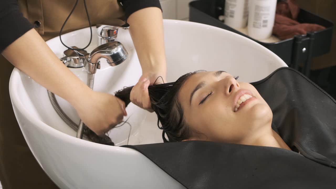 发型师收集并挤压漂亮客户的头发，去除头发中的水分，慢镜头拍摄视频下载