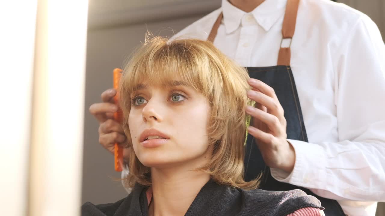 理发后，理发师整理发型和检查头发，慢动作拍摄。视频下载