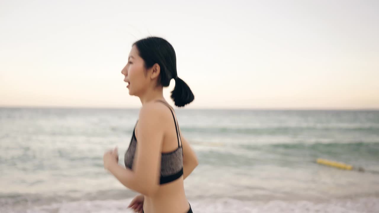 一个年轻女子在沙滩上慢跑的慢镜头。视频下载
