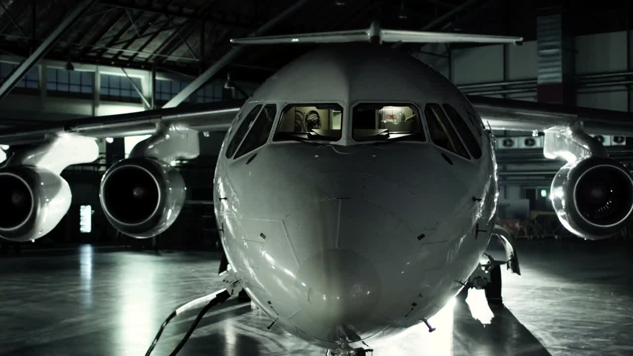 飞机在机库中，从飞机的正面和从窗户发出的光线。库存图片视频购买