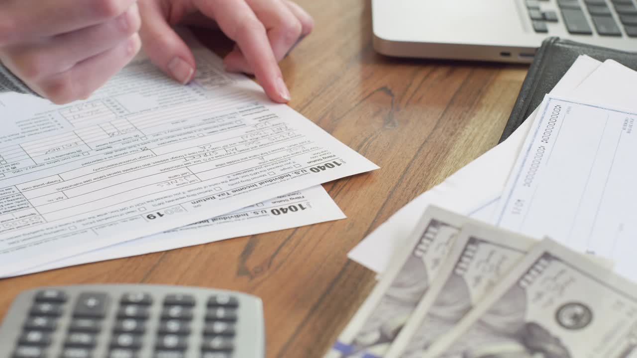 一个女人在家填写所得税申报单的特写镜头。视频素材