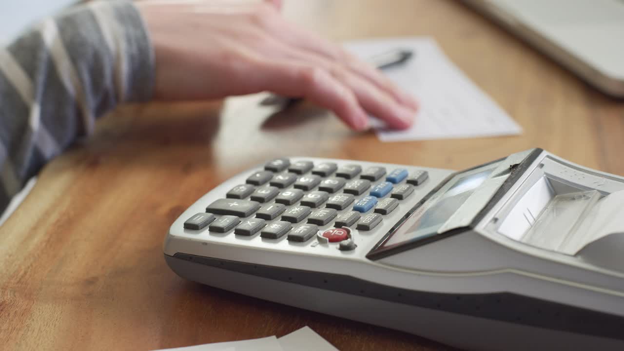一个女人在家里用计算器算所得税的特写镜头。视频素材