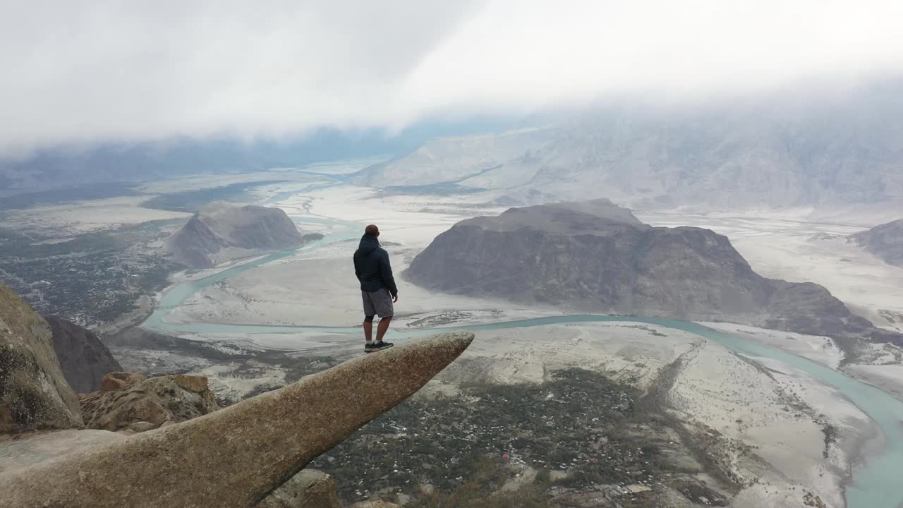 一个人站在岩石上，看着喜马拉雅山上的河流视频下载