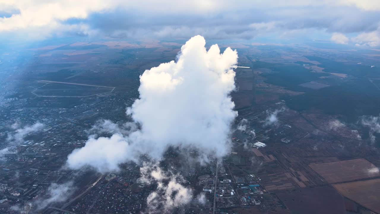 从飞机窗口俯瞰，远处城市在暴风雨前被蓬松的积云覆盖视频素材