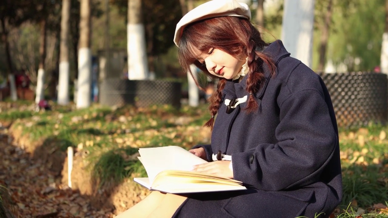 秋天，日落时分，一个女人在外面看书。视频素材
