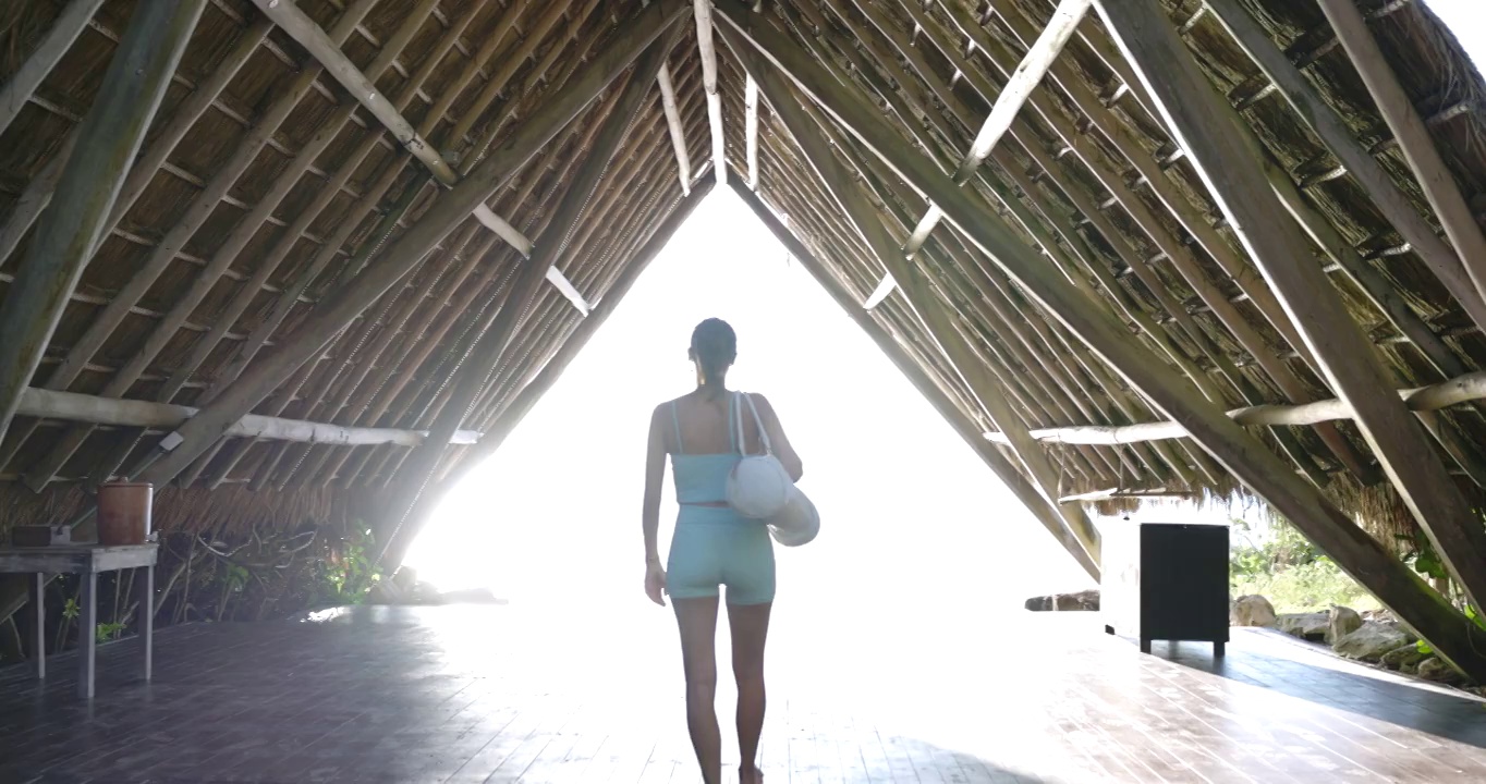 宽镜头后视图的女人走进海洋前瑜伽馆在热带度假视频素材