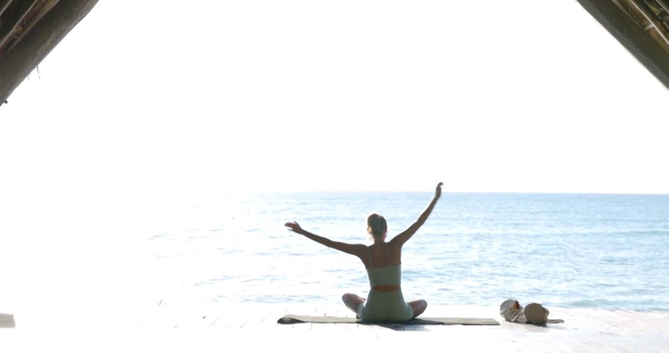 在热带度假胜地的海滨亭子里，一名女子在练习瑜伽前热身视频素材