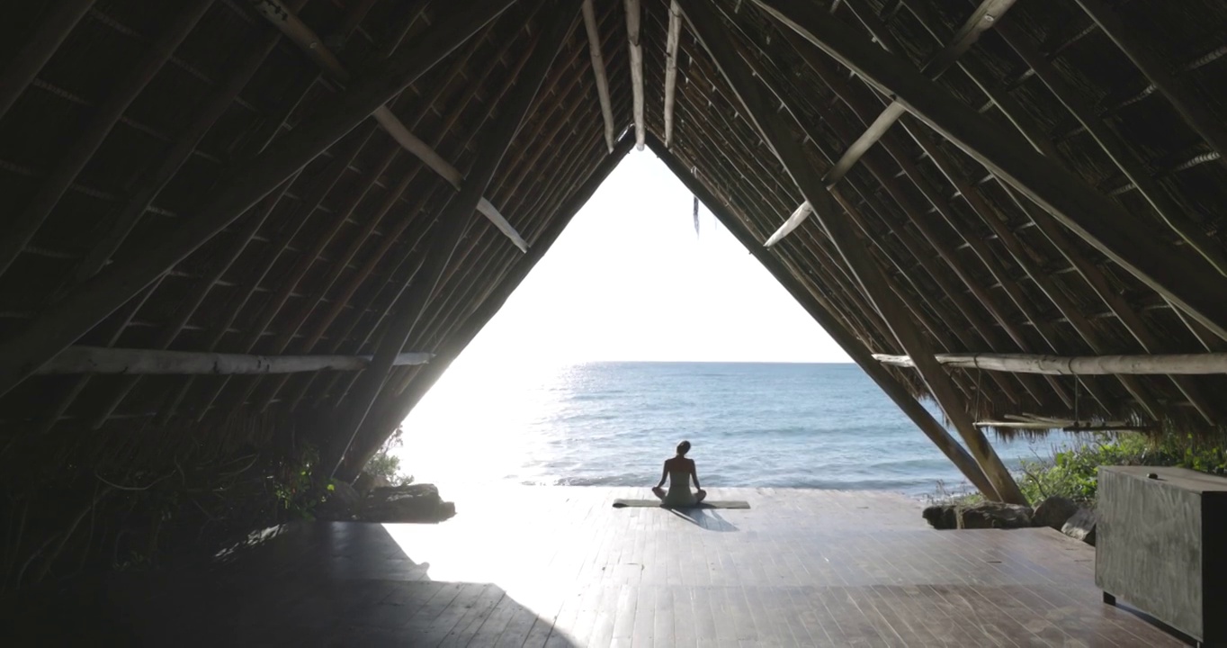 在热带度假胜地的海滨凉亭练习瑜伽后放松的女人的极端宽镜头视频素材