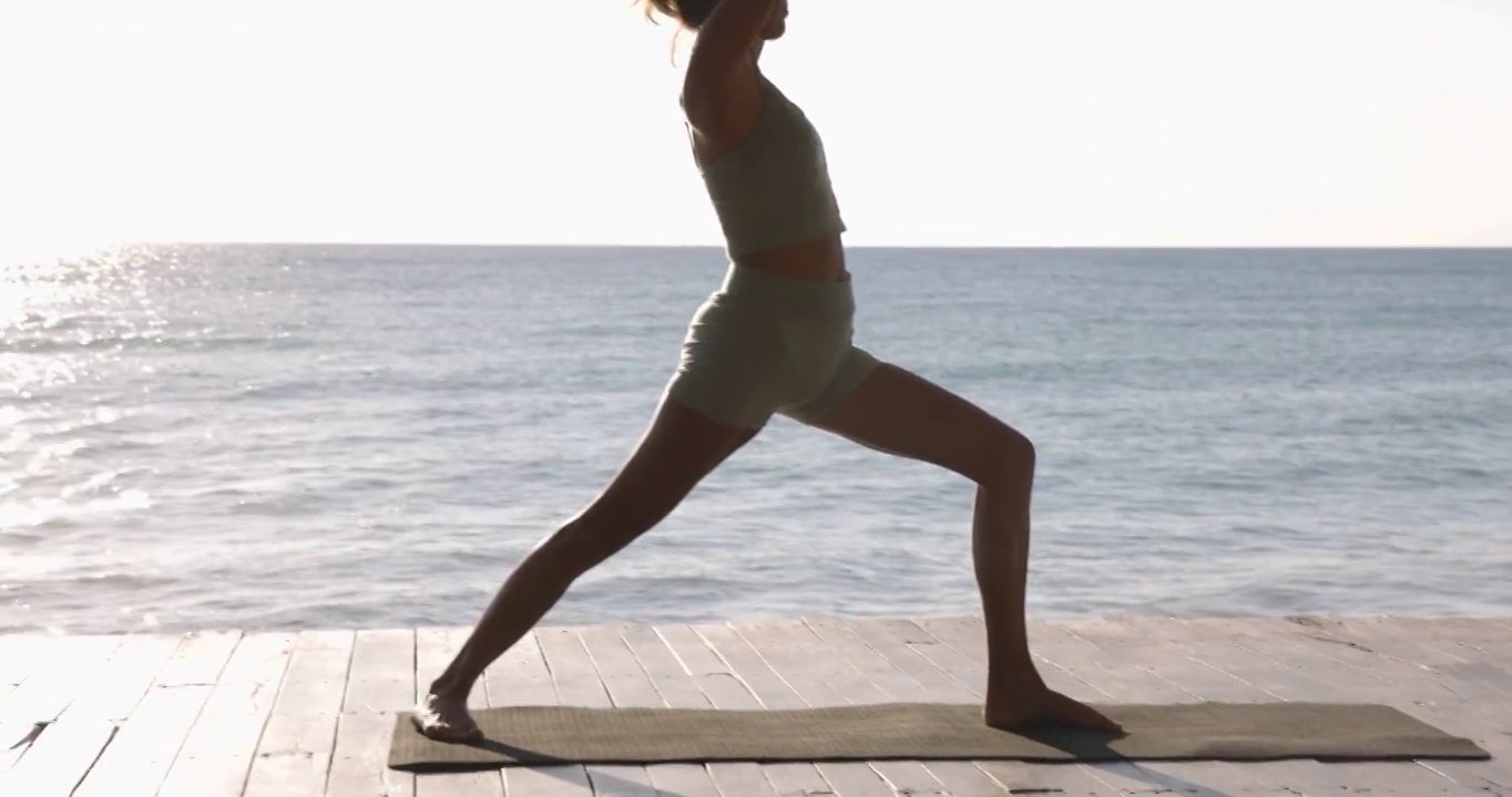 在热带度假胜地的海滨凉亭练习瑜伽的妇女中宽镜头视频素材