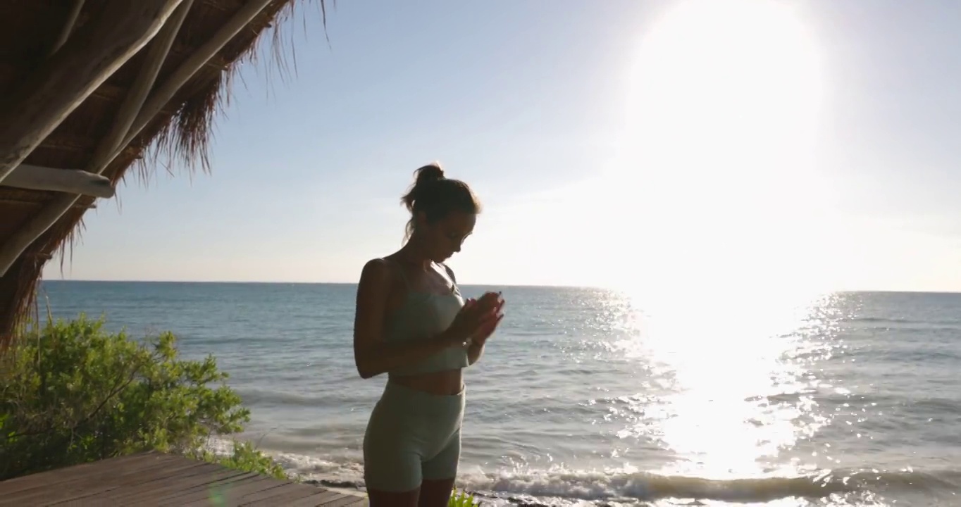在热带度假胜地的海滨凉亭练习瑜伽的女性的中宽镜头视频素材