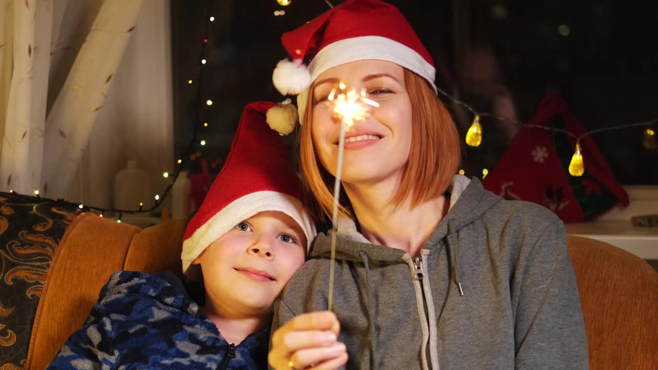 妈妈和儿子在新年帽和燃烧的烟火。新年，圣诞心情。视频素材