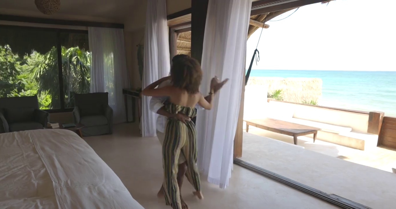在热带度假胜地的豪华套房中，一对夫妇跳舞的广角镜头视频素材