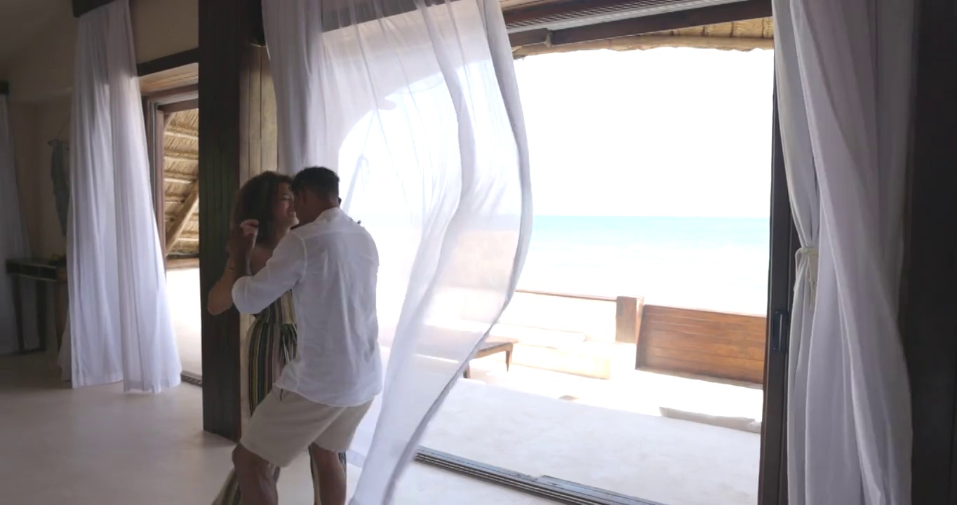在热带度假胜地的豪华套房中，一对夫妇跳舞的广角镜头视频素材