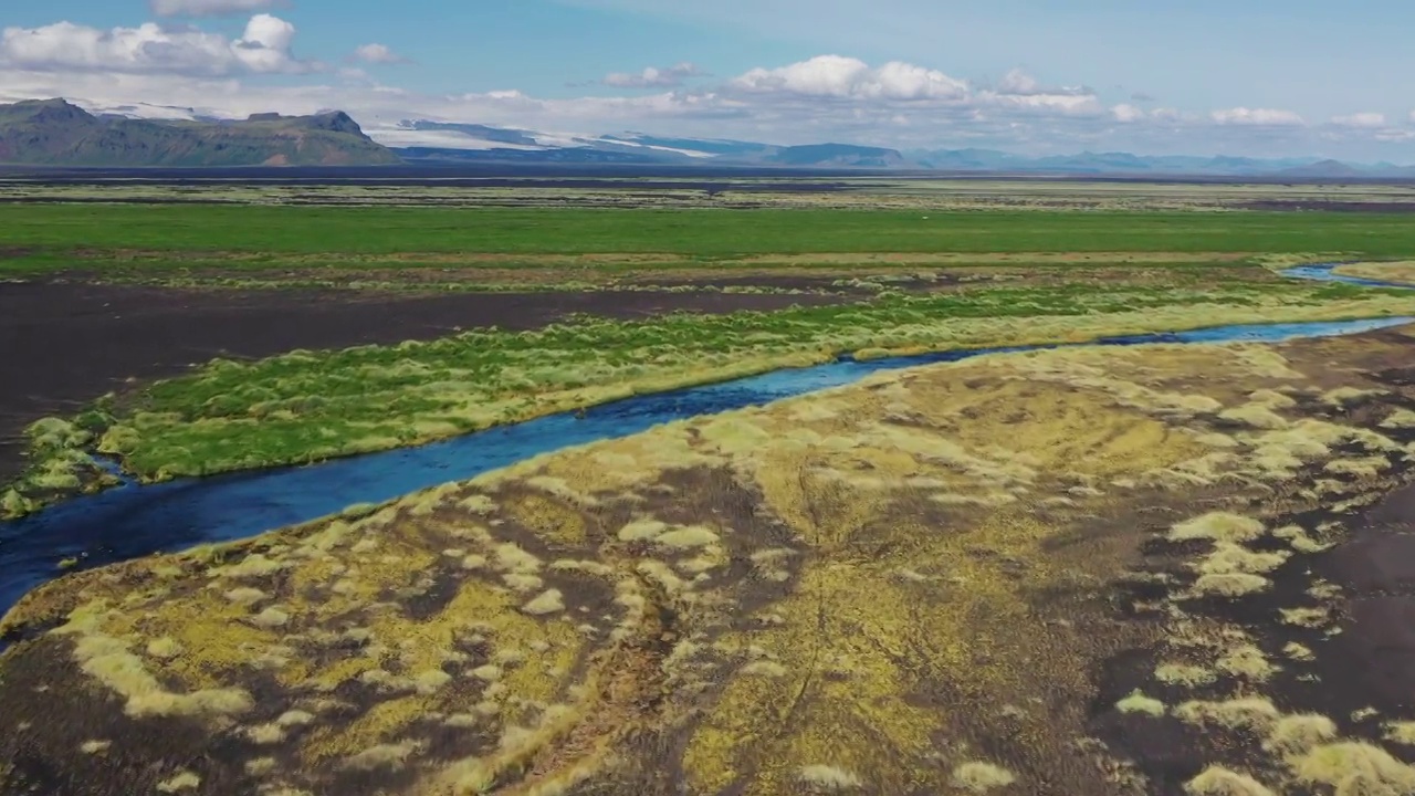 低空飞行的无人机拍摄的照片显示，在冰岛的夏季，一条河流穿过一片郁郁葱葱的火山景观视频素材