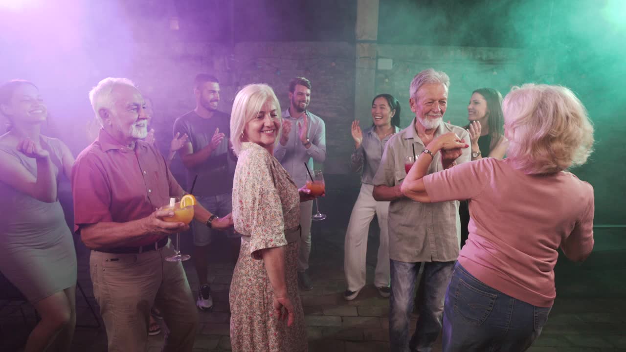 酒吧里，无忧无虑的老夫妇在年轻人中间跳舞。视频素材