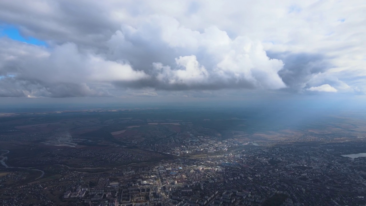 从高空的飞机窗口鸟瞰，远处的城市被暴雨前形成的蓬松的积云所覆盖视频素材