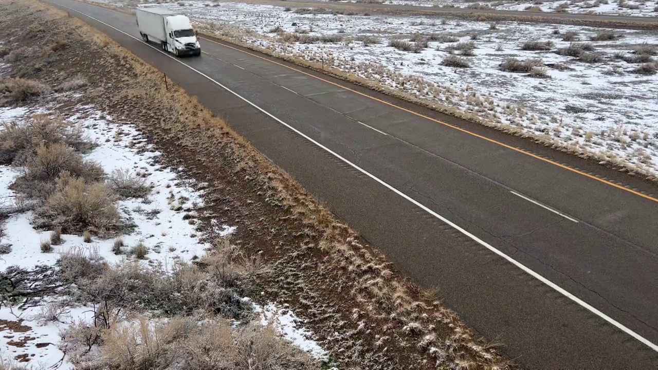 在潮湿的雪地高速公路上，轿车和半卡车擦肩而过视频素材