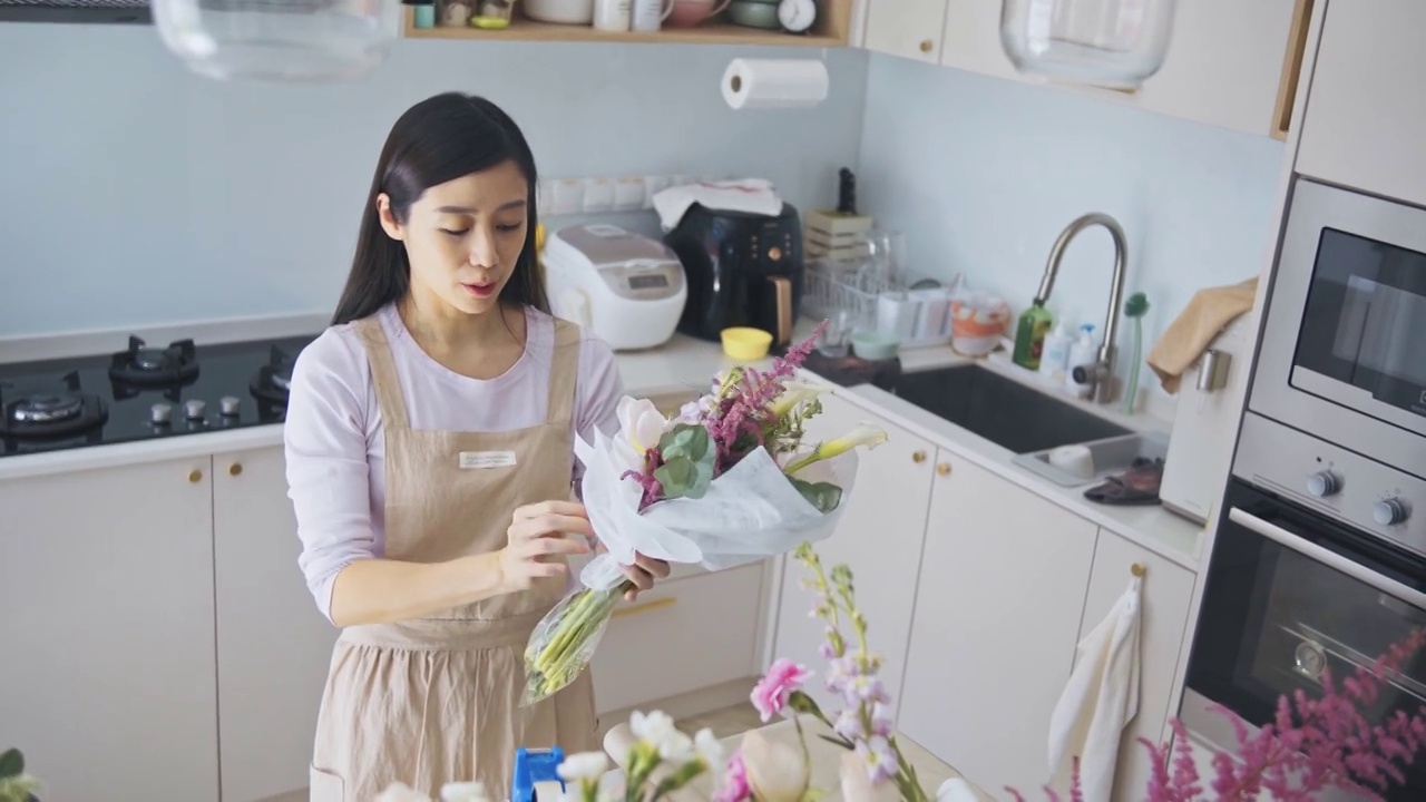 亚洲华人女性花商，小企业主包装花束在厨房工作，在家里运行一个小生意的日常工作视频素材