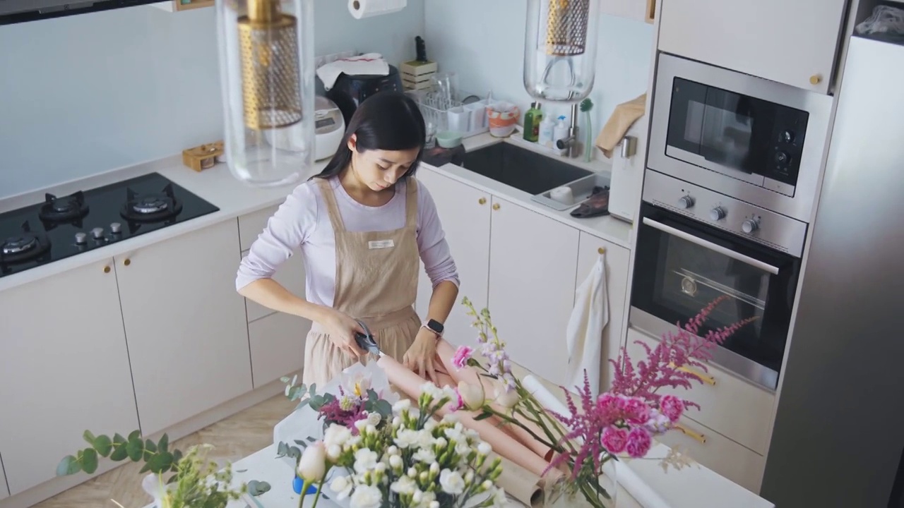 亚洲华人女性花商，小企业主，在厨房为花束剪包装纸，在家里工作，日常运作一个小生意视频素材