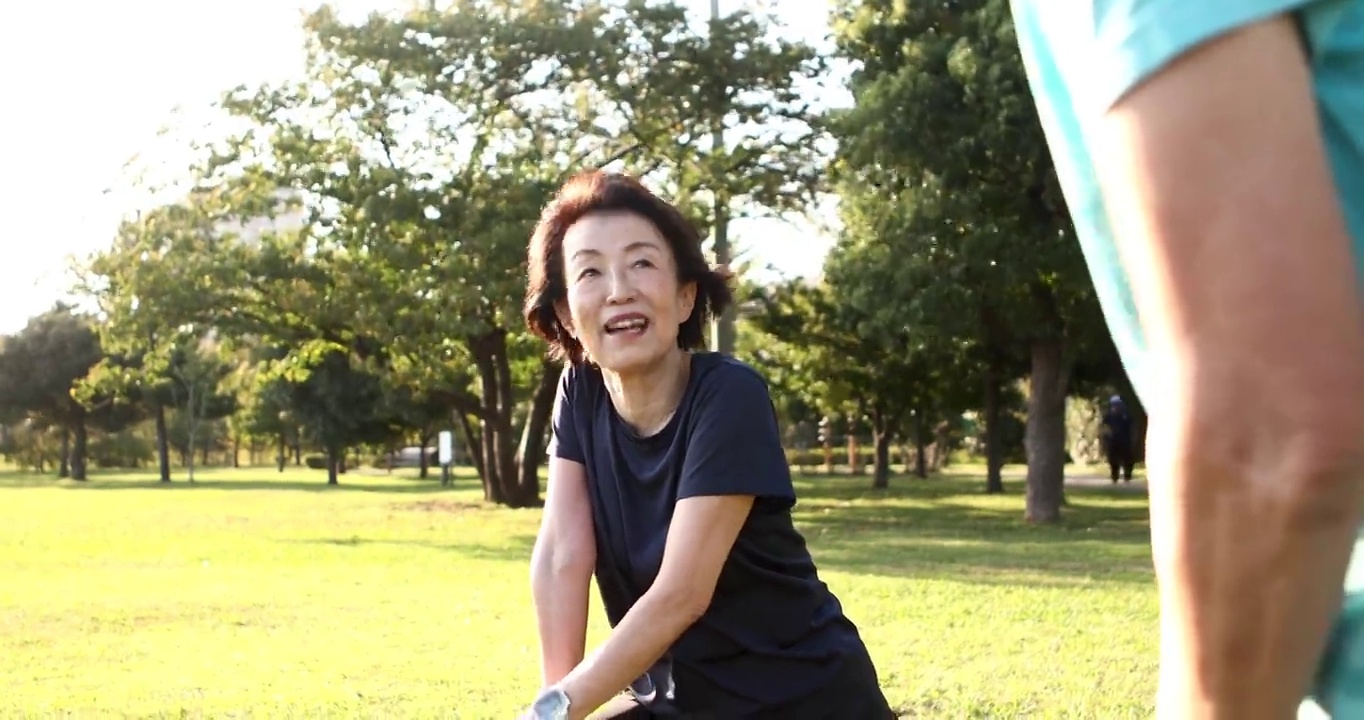 一位年长的女性在开始在公园慢跑之前会做一些预备运动视频素材