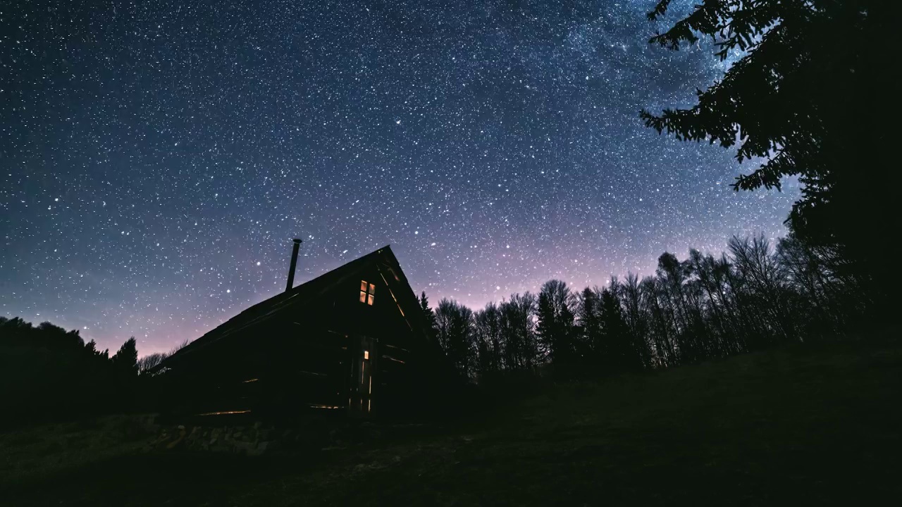 童话般的夜空，在原始森林的小木屋上，银河星系的数百万颗星星。天文学视频下载