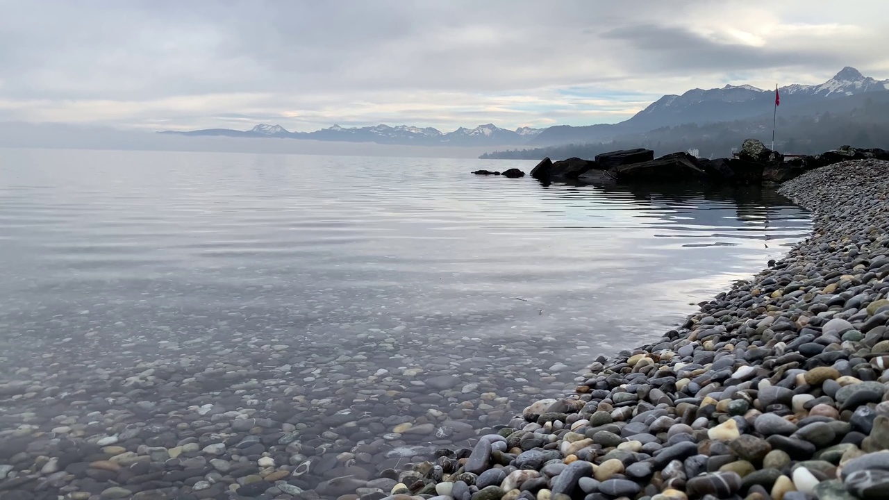 无声的4K视频，日内瓦湖的卵石海滩和阿尔卑斯山的冬天视频素材