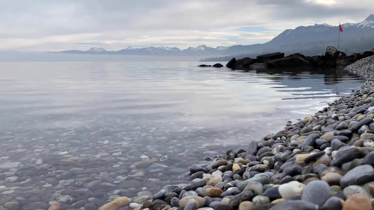 无声的4K视频拍摄了日内瓦湖卵石滩和冬天的山脉视频下载
