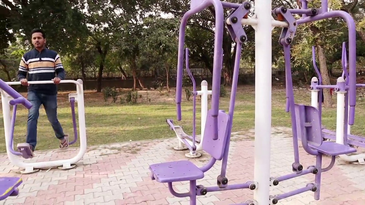 平移镜头，健力士步行者机，年轻人在公园户外健身步行者机上锻炼视频下载