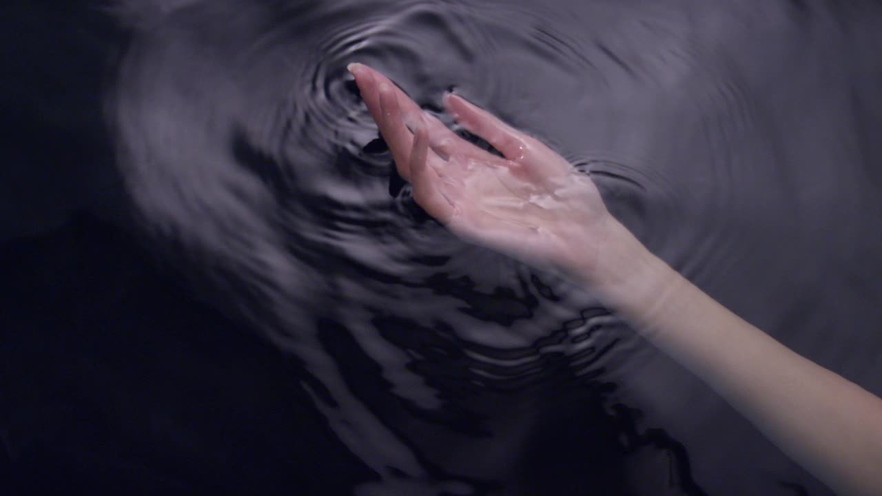 光滑如丝的水面。女性用手轻轻泼洒并触摸液体视频素材