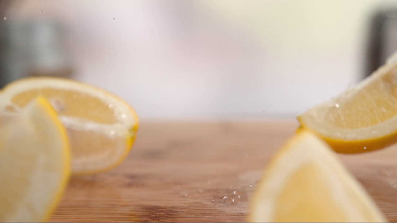 柠檬片落在木桌上，水滴在慢动作中跳跃飞溅视频素材