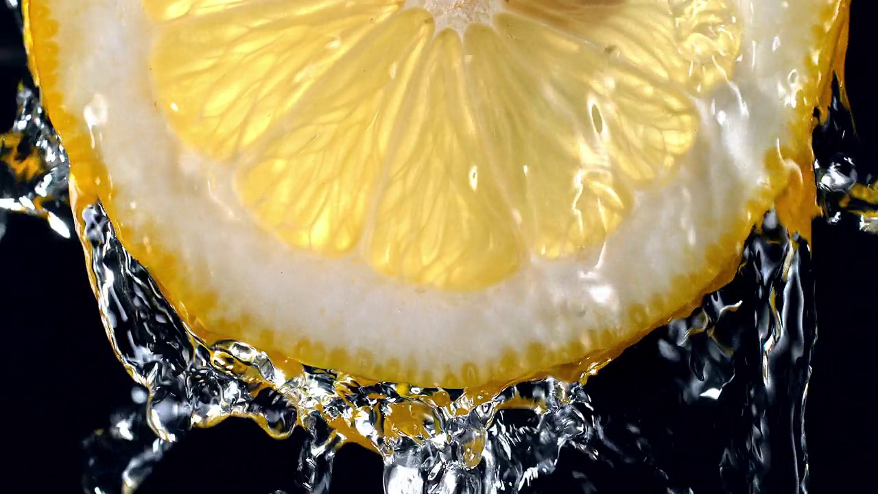 柠檬片(背光)从顶部的水溅到慢动作视频素材