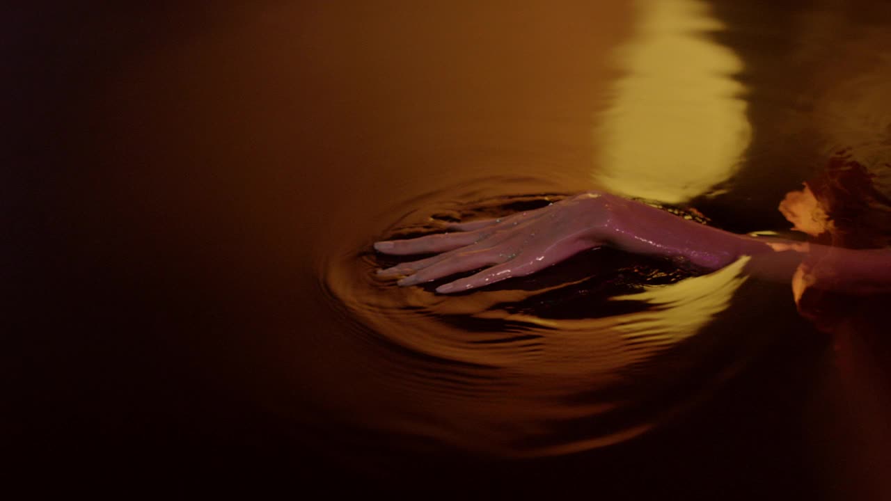 金色的，光滑的水面。女性用手轻轻泼洒并触摸液体视频下载