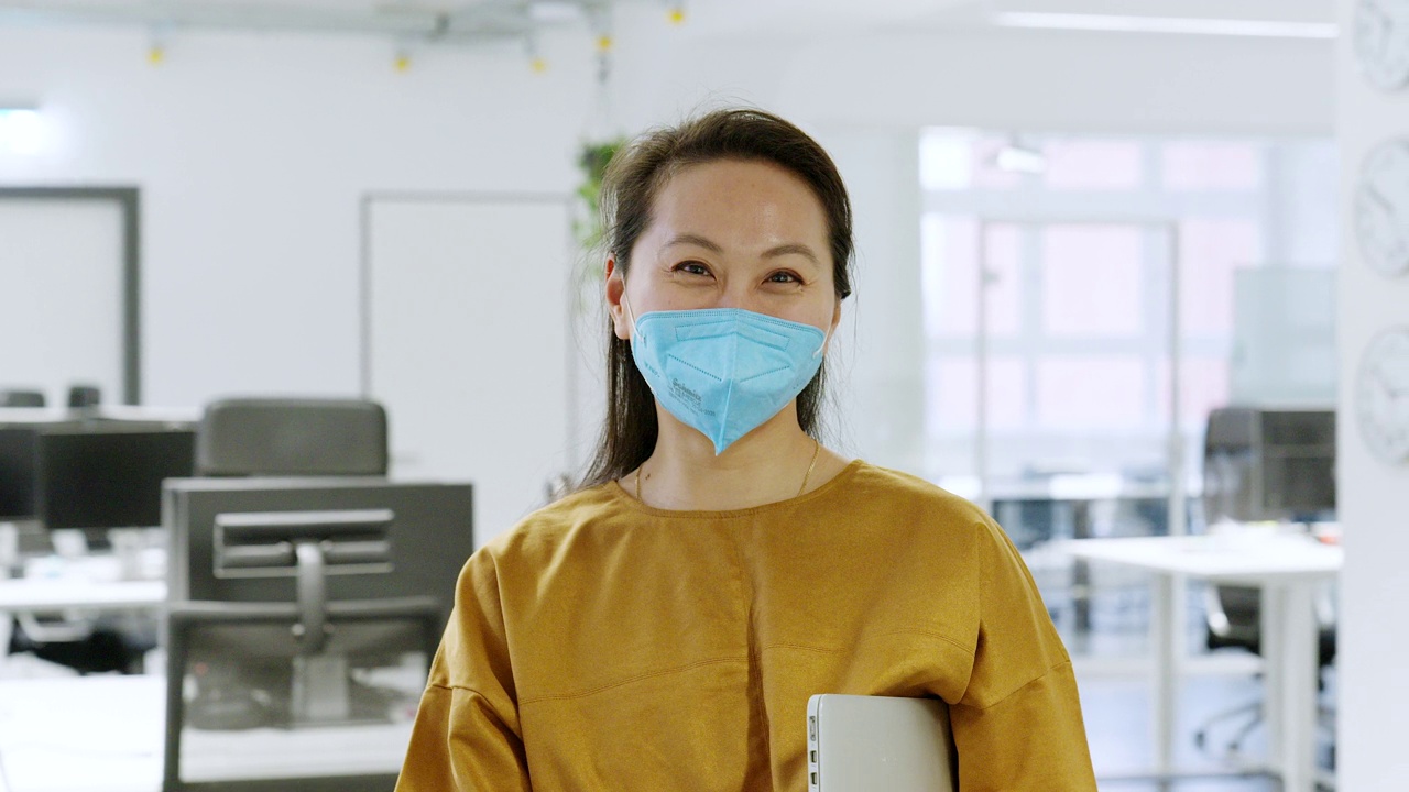 亚洲年轻女商人的肖像，带着面具站在办公室视频素材