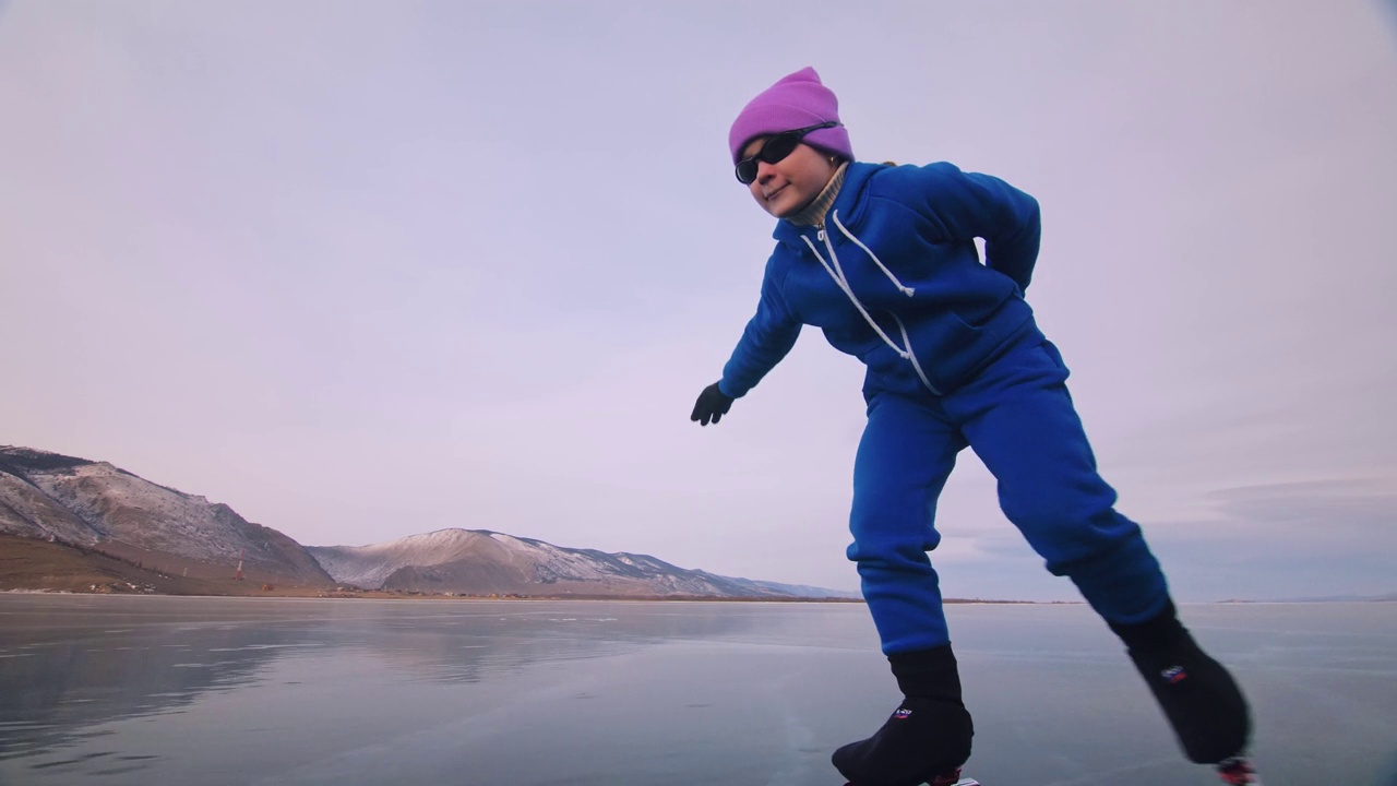 这个女孩在冰上进行速滑训练。冬天孩子们穿着蓝色运动服，戴着运动眼镜溜冰。儿童速滑运动视频购买