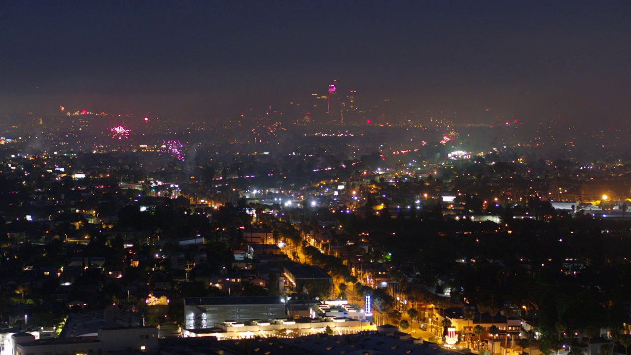 空中拍摄的烟花庆典在灯火辉煌的城市，无人机向后飞在房屋上空-洛杉矶，加利福尼亚视频下载