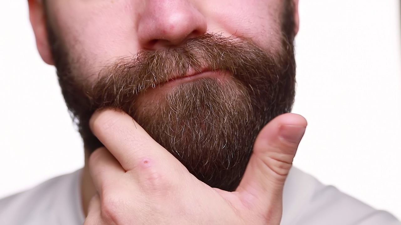 男性特写肖像，抚摸他的胡子。视频下载