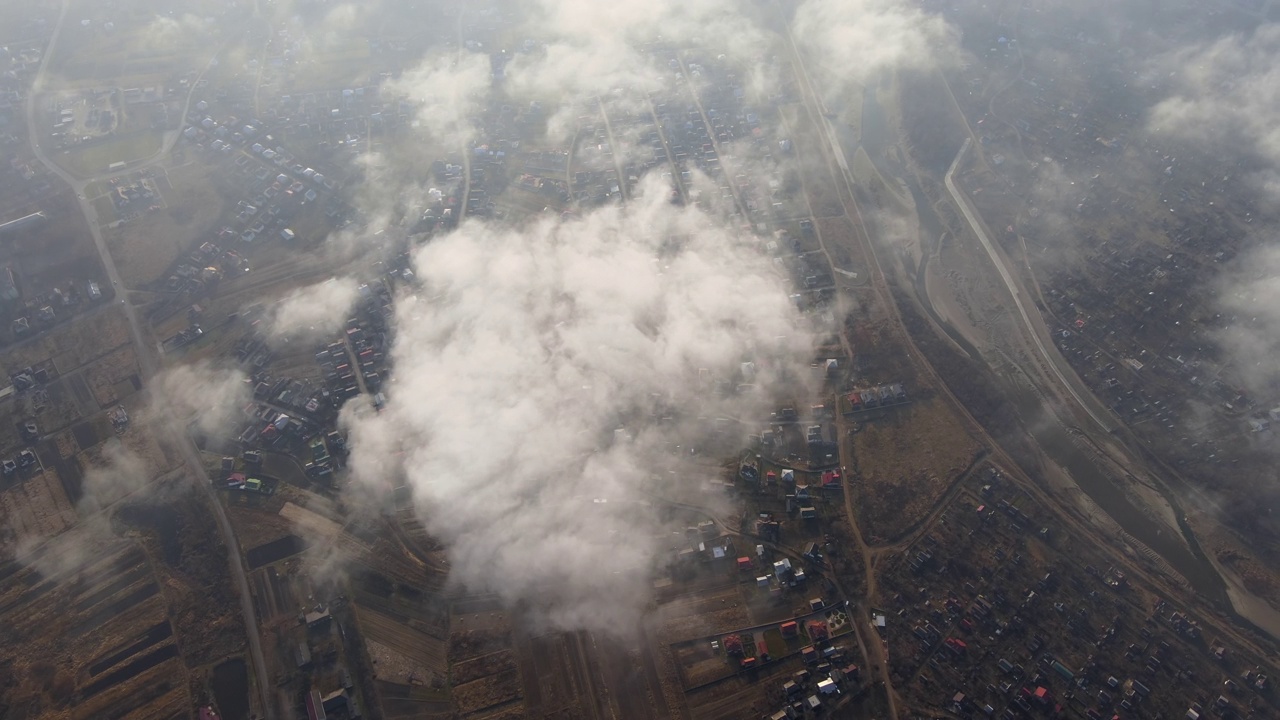 高空鸟瞰图，远处的城市被暴雨前形成的蓬松的积云所覆盖。飞机角度多云的景观视频素材