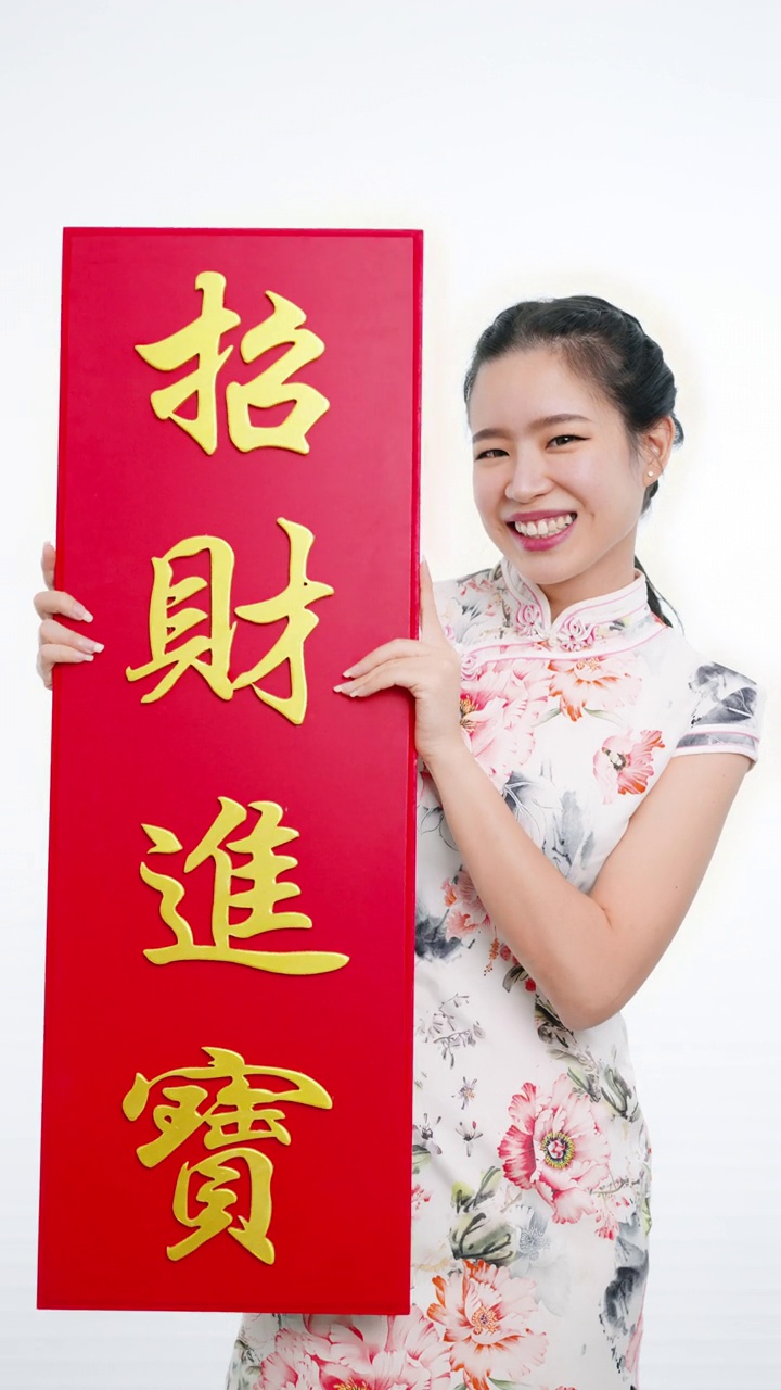 中国/亚洲妇女穿着旗袍，递上大的红色招牌，表示新年快乐，富有，幸福和幸运视频下载